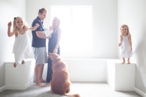 family with golden retriever and new baby and jumping sister