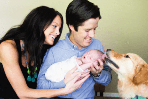 couple with dog licking new baby