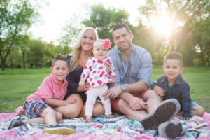 family on quilt in park