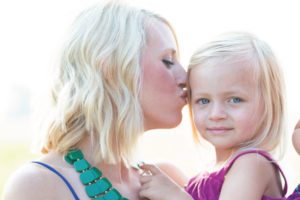 mother kissing young daughter
