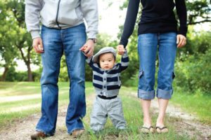 couple walking baby in striped sweater