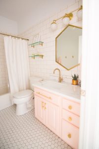 Modern Glam Blush Girls Bathroom Design gold hexagon mirror blush cabinets gold hardware white hexagon floor glass shelves pink bathroom cabinets gold orb sconce-1-3