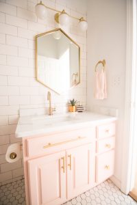 Modern Glam Blush Girls Bathroom Design gold hexagon mirror blush cabinets gold hardware white hexagon floor glass shelves pink bathroom cabinets gold orb sconce-1-3