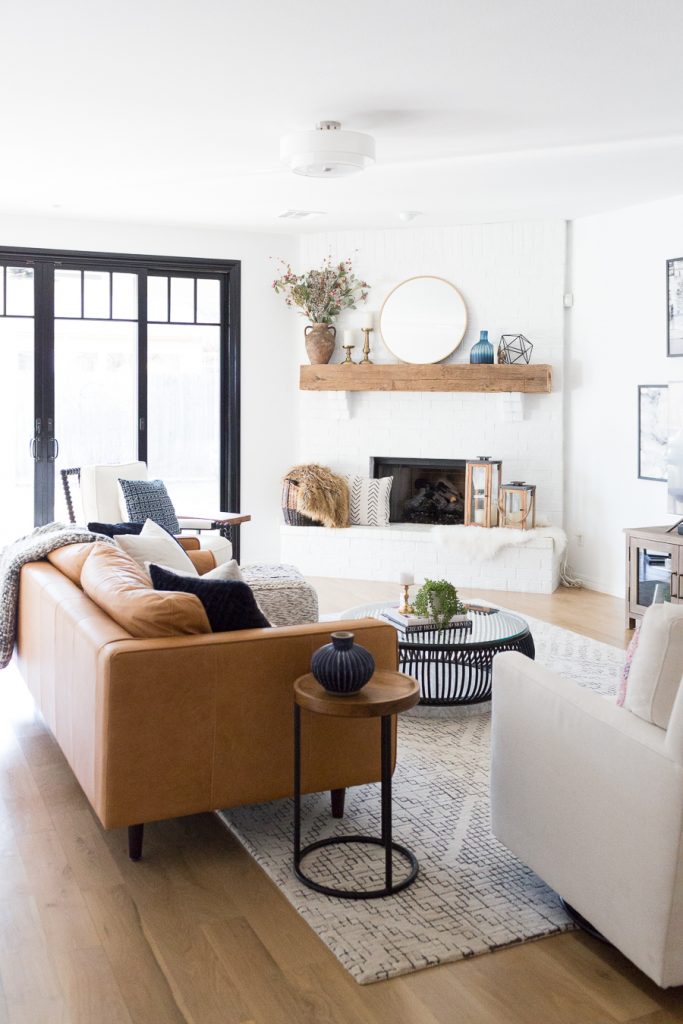 Tulsa Remodel Reveal Modern White Farmhouse black windows and doors modern leather sofa article sven sofa white brick fireplace wood beam mantle tv gallery wall-1