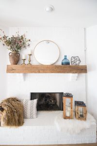 Tulsa Remodel Reveal Modern White Farmhouse white brick fireplace wood beam mantle gold round mirror-1