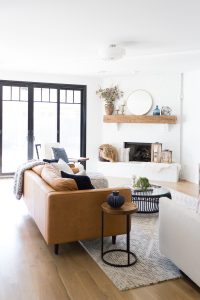 ALUMINUM CLAD Affordable alternatives to steel windows and doors white living room with black aluminum clad sliding doors and a white painted brick fireplace with a round mirror hanging above it article Sven leather sofa on a west elm stone tile rug with a black cb2 coffee table