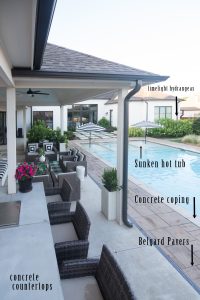 How to Design a Beautiful Pool and Outdoor Living Area best outdoor patio pavers black and white outdoor umbrellas rectangle pool sunken hot tub concrete pavers white house black windows outdoor concrete countertops