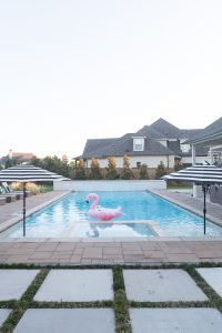 How to Design a Beautiful Pool and Outdoor Living Area buffalo check outdoor rug Target outdoor club chairs black and white outdoor pillows cement countertops outdoor living area decor ideas wicker pool lounger best affordable pool loungers black and white outdoor umbrellas rectangle pool design large rectangular pool with sunken hot tub most beautiful rectangle pools concrete pavers with mondo grass concrete pavers with grass growing between them