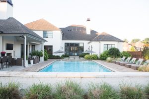 How to Design a Beautiful Pool and Outdoor Living Area buffalo check outdoor rug Target outdoor club chairs black and white outdoor pillows cement countertops outdoor living area decor ideas wicker pool lounger best affordable pool loungers black and white outdoor umbrellas rectangle pool design large rectangular pool with sunken hot tub most beautiful rectangle pools concrete pavers with mondo grass concrete pavers with grass growing between them white brick house with black windows and doors