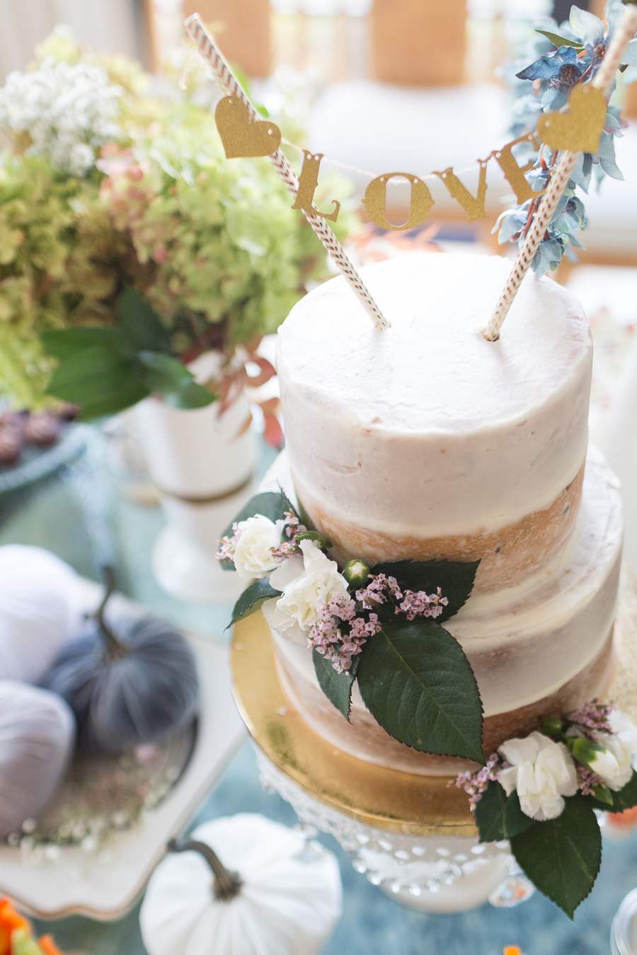 Beautiful Fall Bridal Shower Ideas fall bridal shower cake on a white cake stand surrounded by velvet pumpkins and hydrangeas