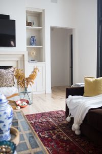 Loveliest Looks of Fall Home Tour Beautiful Fall Home Decor and Fall Fashion Ideas Affordable and Easy Fall Home Decor Tips large living room with pink area rug and a chocolate velvet sofa with leopard pillows and built in bookshelves with chinoiserie vases