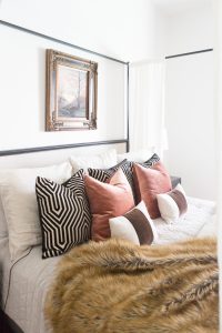 Loveliest Looks of Fall Home Tour Beautiful Fall Home Decor and Fall Fashion Ideas white master bedroom with a black canopy bed and a gold and black frame hanging above the bed with fall tree art linen bedding with black and white graphic mary mcdonald fabric velvet pillows behind blush velvet pillows and a fur throw on the bed