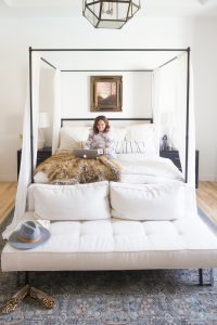 Loveliest Looks of Fall Home Tour Beautiful Fall Home Decor and Fall Fashion Ideas lifestyle blogger in Aerie camo jogger set sitting on a canopy bed with linen bedding and a fur throw with a fall canvas photo of a tree hanging above the bed and a circa caged lantern pendant hanging from the ceiling
