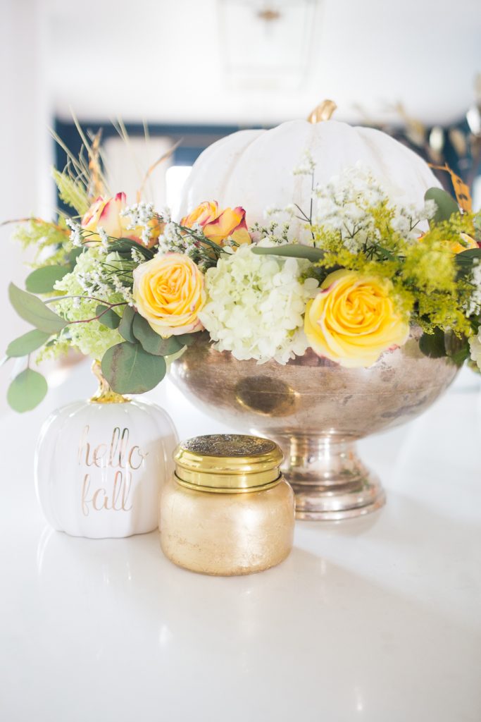 DIY Silver Urn Pumpkin Centerpiece for Fall hydrangeas and eucalyptus and roses inside of a silver urn with a ceramic pumpkin for a Thanksgiving centerpiece sitting beside a fall Anthropologie candle and hello fall pumpkin