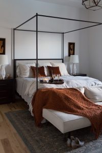 Simple Ways to Decorate for the Holidays from West Elm master bedroom with a canopy bed and a copper chunky knit throw and copper rust velvet pillows