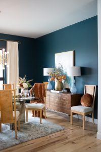 Simple Ways to Decorate for the Holidays from West Elm dark green painted dining room with glass and gold marble dining room table and burl wood chairs with a holiday tablescape with gold candlesticks and a large silver faceted vase with fresh flowers