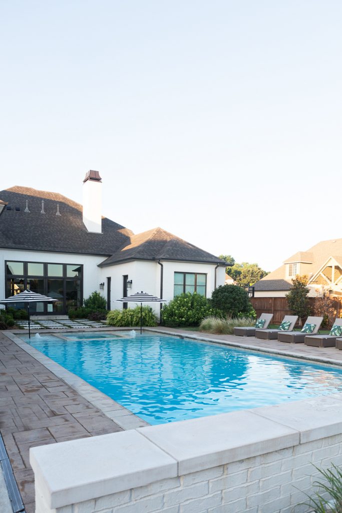 How to Prepare Your Patio for Spring with the Home Depot featuring a blue pool and lounge chairs and striped umbrellas