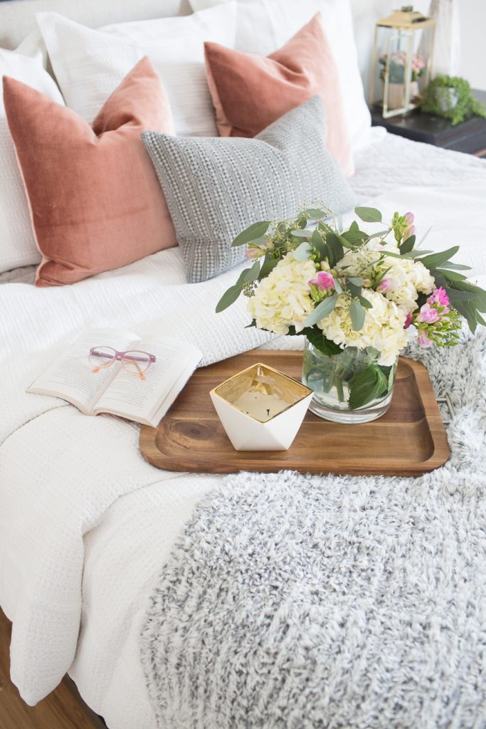 Refresh Your Master Bedroom and Bath with Pottery Barn wooden tray sitting on bed with pastel pillows and a beautiful floral arrangement