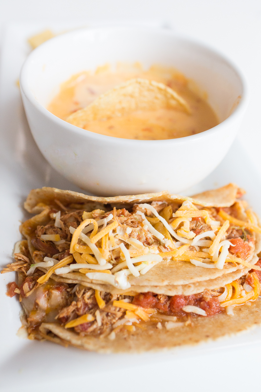 Two Minute Crockpot Chicken Ranch Tacos-1 soft tacos on a long white plate with a bowl of queso and chips