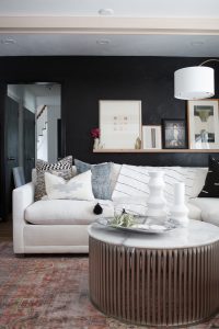 CC and Mike Kane Project Remodel Reveal white L shaped sectional on a terracotta loren rug from CC and Mike THE SHOP round coffee table black accent wall with wood art ledge