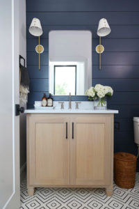CC and Mike Frisco I Project Reveal navy shiplap wall with white oak vanity in a bathroom with silver mirror and brass and white sconces black hardware