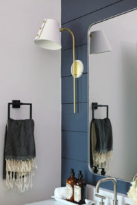CC and Mike Frisco I Project Reveal navy shiplap wall with white oak vanity in a bathroom with silver mirror and brass and white sconces black hardware