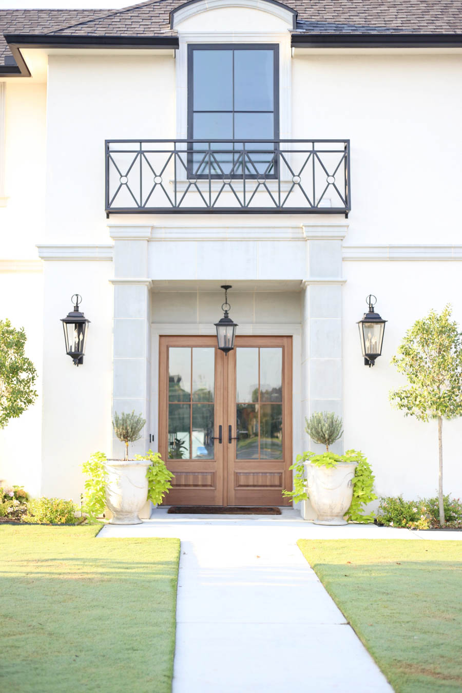 CC and Mike Frisco I Project Reveal-2 white European stucco exterior with cast stone around wooden door and topiary planters