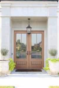 CC and Mike Frisco I Project Reveal-2 white European stucco exterior with cast stone around wooden door and topiary planters beautiful wooden front doors