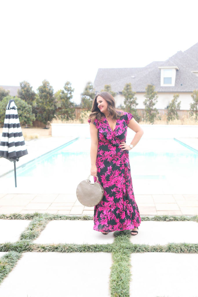 15 Must Have Walmart Fashion Items for Spring Carissa Miller standing by a rectangular pool with hot tub and black and white umbrella in a black and pink palm print wrap dress by Sofia Vergara Walmart