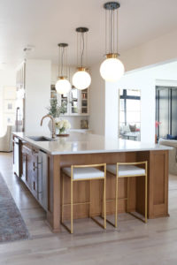 CC and MIke Kitchen Remodel Reveal large natural wood island with quartz countertops and gold bar stools black and gold pendants Ann sacks patterned backsplash gold Brizo faucet large Kallista stainless steel sink open floorpan